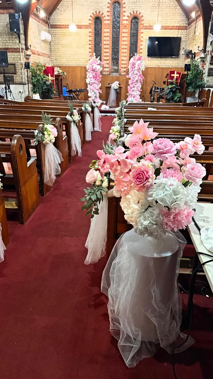 Church aisle with pink and white florals and tulle on the pews